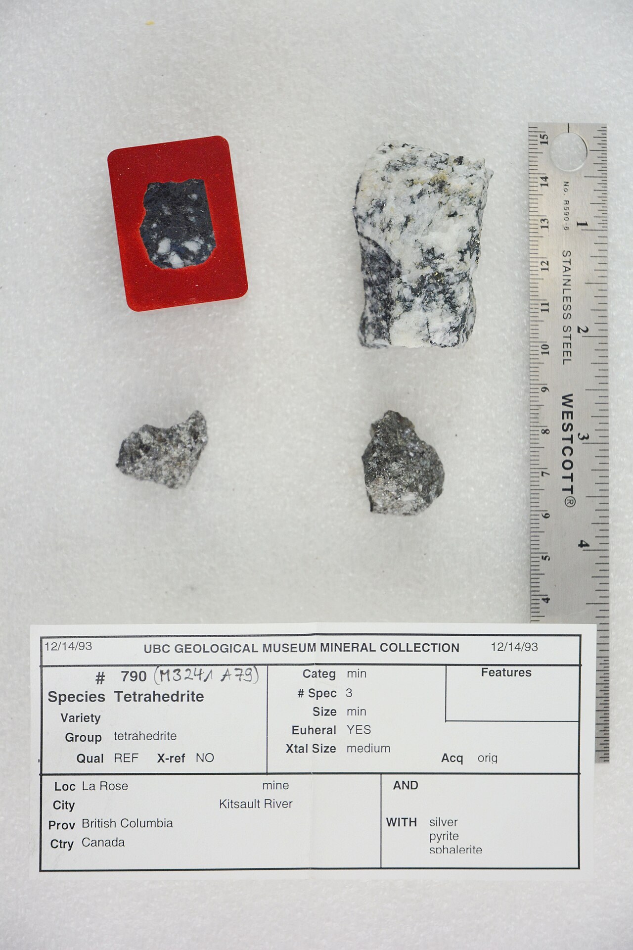 Three small mineral specimens beside a ruler and a museum collection label