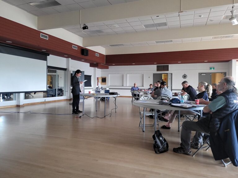 Attendees at tables listen to a presenter.