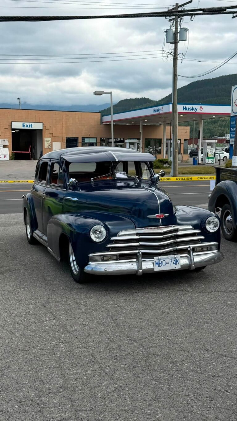 A vintage dark blue car parked on the lot.