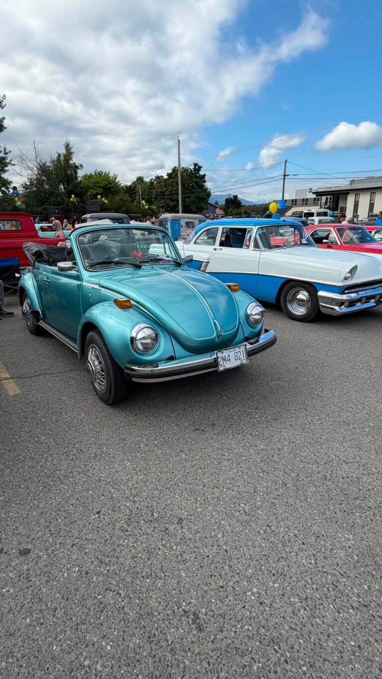 A turquoise Volkswagen Beetle convertible among other classic cars.