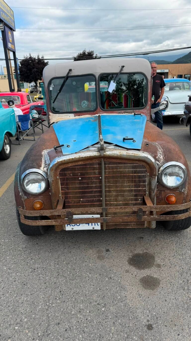 Front of a weathered vintage truck with a blue hood panel.