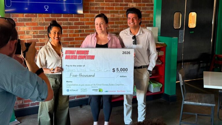 Three people hold a large $5,000 competition cheque while a photographer takes their picture.