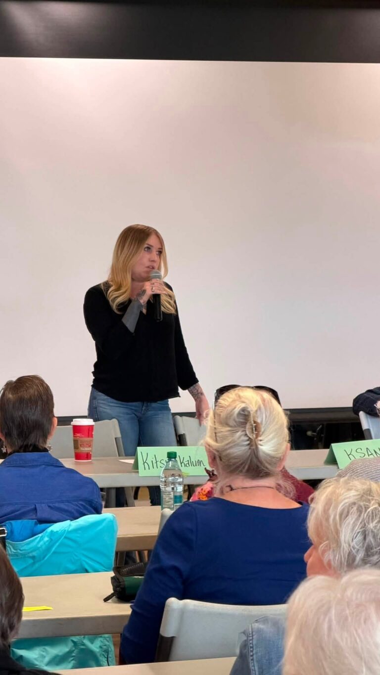 A woman speaks into a microphone in front of the audience.
