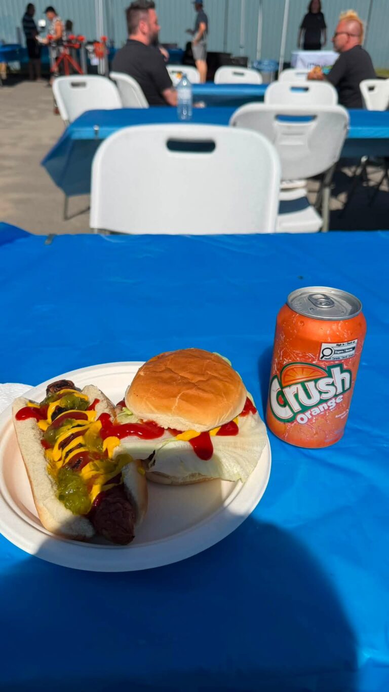 A burger and a hot dog with a can of Crush on a table.