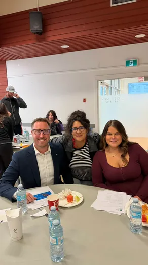 Three attendees smile for the camera at a round table at the BC Mining Roadshow in the Terrace Sportsplex banquet room.